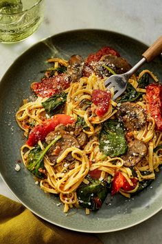 a plate of pasta with mushrooms, spinach and tomatoes