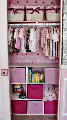 an organized closet with pink drawers and white baskets filled with baby's clothing, books and toys