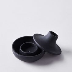 two black bowls sitting next to each other on a white surface