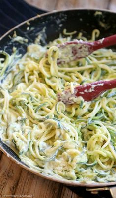 a pan filled with pasta and sauce on top of a wooden table