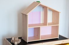 a wooden doll house sitting on top of a table