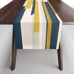 the table is covered with a multicolored striped table runner on it's wooden legs