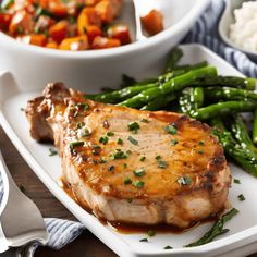 a white plate topped with meat next to green beans and carrots on a wooden table