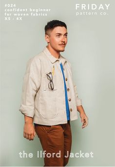 a man in a jacket and tie with scissors on his shirt, standing against a gray background