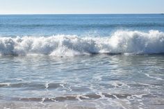 an ocean wave is breaking on the beach