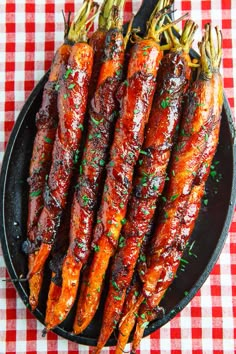 cooked carrots on a black plate with parsley and red checkered tablecloth