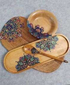 three wooden bowls and two spoons with designs on them