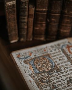 an open book sitting on top of a wooden table next to bookshelves filled with old books