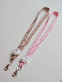 two pink and white crocheted leashes with flowers on them, one is attached to