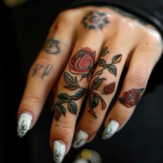 a woman's hand with tattoos on it and roses on the ring finger tattoo