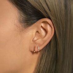 a close up of a woman's ear with two small gold rings on it