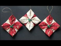 two red and white origami ornaments hanging from strings on a black table top