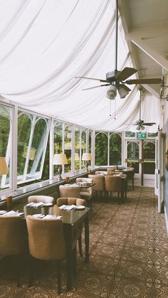 the inside of a restaurant with tables, chairs and ceiling fans on each side of the room