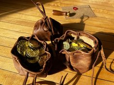 two brown bags filled with coins sitting on top of a wooden floor