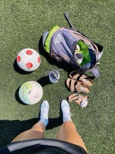 a person's feet are shown next to a soccer ball and other sports equipment