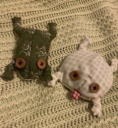 two stuffed animals laying on top of a bed next to each other with buttons in their eyes