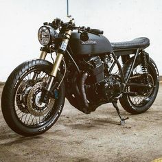 a black motorcycle parked in front of a white wall with lights on it's side