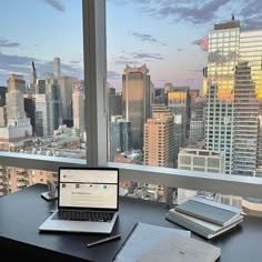 an open laptop computer sitting on top of a desk in front of a large window