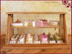 a display case filled with lots of different types of cakes and cupcakes on top of wooden shelves