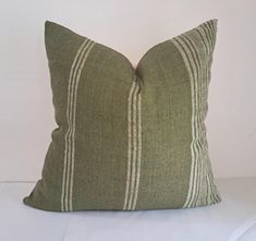 a green and white striped pillow sitting on top of a bed