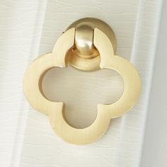 a close up of a door handle on a white surface with a gold flower design