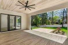 an empty living room with wood floors and a ceiling fan in the middle of it