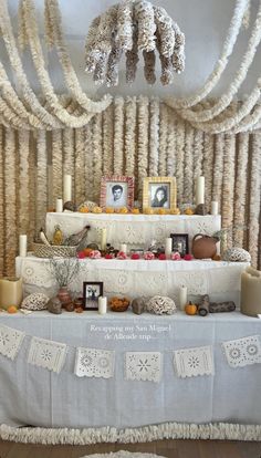 a table topped with pictures and candles under a chandelier covered in white lace