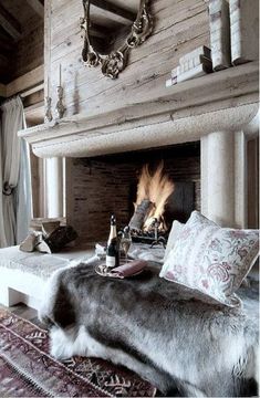 a living room filled with furniture and a fire place next to a bed covered in blankets