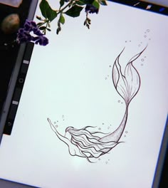 a drawing of a mermaid tail on a sheet of paper with purple flowers in the background