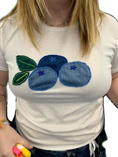 a woman wearing a white shirt with blue flowers on the front and green leaves on the back