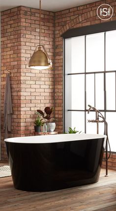 a bath tub sitting next to a brick wall in a room with wooden flooring