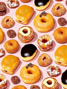 many donuts with different toppings are arranged on a pink surface