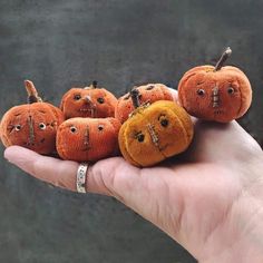 a hand holding five small pumpkins with faces on them