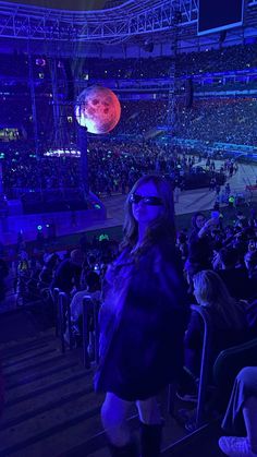 a woman standing in front of an audience at a concert with her face covered by blue light