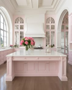 a large kitchen with pink cabinets and white counter tops, along with an island in the middle