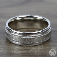 a wedding band with an engraved design on the outside and inside, sitting on a wooden surface