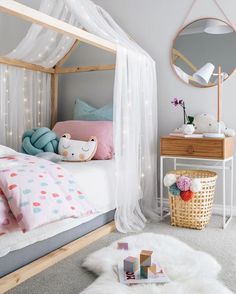 a bedroom with a white canopy bed, pink and blue decor and lights on the ceiling