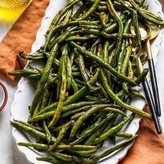 a white plate topped with green beans and chopsticks