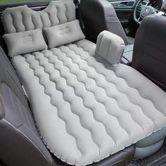 an inflatable car bed is sitting on the back seat of a car with two pillows