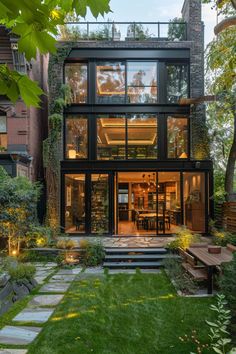 a modern house with large glass windows and lots of greenery on the front lawn