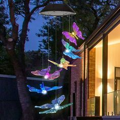 some lights that are hanging in the air near a tree and building at night time