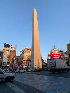 an obelisk stands tall in the middle of a busy city street at sunset