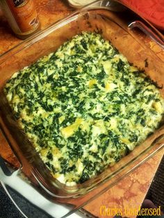 a casserole dish with spinach and cheese in it sitting on a table