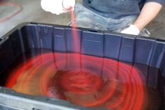 a man is pouring red liquid into a container