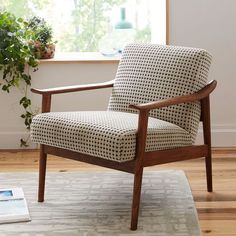 a chair sitting on top of a rug in front of a window next to a potted plant