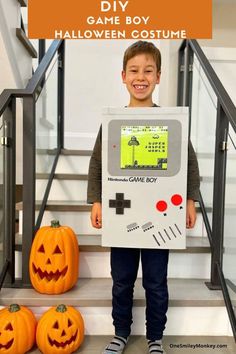 a young boy is holding up a video game costume while standing next to two pumpkins