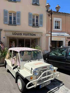 an old white car parked in front of a building