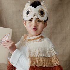 a young boy wearing a mask and holding a piece of paper