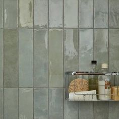 a glass shelf with bottles and soaps on it in front of a tiled wall