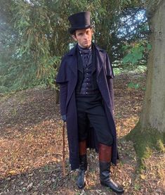 a man dressed in period clothing standing next to a tree